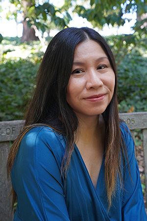 Grace Loh Prasad, seated in a royal blue blouse, with long dark hair and a slight smile