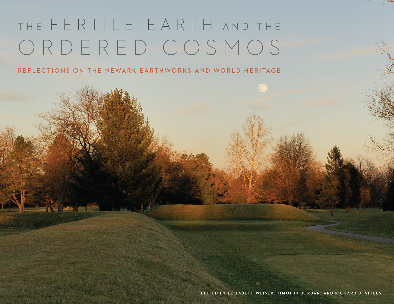 Front cover of The Fertile Earth and the Ordered Cosmos: Reflections on the Newark Earthworks and World Heritage, Edited by M. Elizabeth Weiser, Timothy R. W. Jordan, and Richard D. Shiels, featuring a photo of grass-covered earth mounds, trees in the background, and the full moon in the early twilight sky.